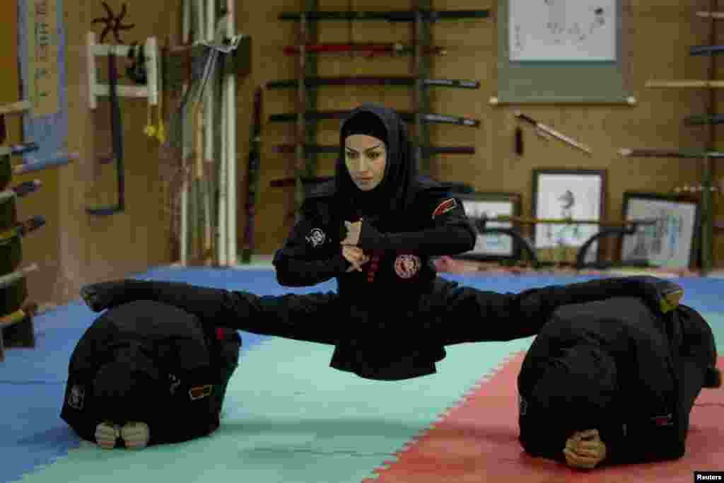 An Iranian woman performs a split as members of various ninjutsu schools showcase their skills to the media in a gym in Karaj, near Tehran. (Reuters/Caren Firouz)