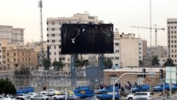 Vehicles drive past a burnt billboard as daily life returns to the streets of Tehran on January 19 following nationwide protests.