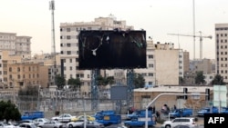 Vehicles drive past a burnt billboard as daily life returns to the streets of Tehran on January 19 following nationwide protests.