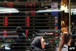 Women walk past a currency exchange office in Tehran on June 15.
