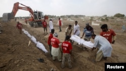 Pakistanda ýaşaýjylar howanyň aşa gyzmagy netijesinde heläk bolan adamlaryň jesetlerini jaýlaýarlar. 26-njy iýun, 2015 ý.