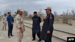 A Pakistani border security official (R) and an Iranian border official meet at Zero Point in the Pakistan-Iran border town of Taftan, October 16, 2018