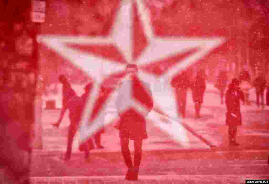 Прохожие в Кишиневе и баннер Партии социалистов, 23 февраля, за день до парламентских выборов в Молдове (AP/Vadim Ghirda) 