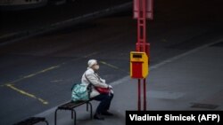 Žena s maskom čeka autobus