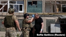 Пораненому внаслідок російської атаки чоловіку надають першу допомогу, Харків, 15 липня 2026 року