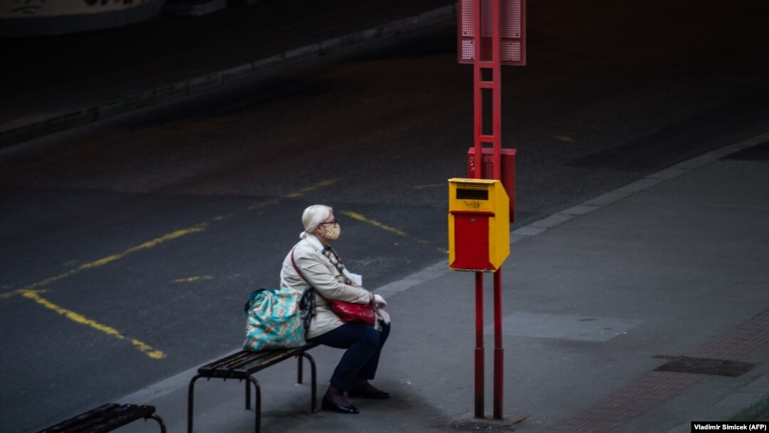 Žena s maskom čeka autobus