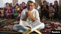 Tajikistan -- The keeper of the Mausoleum of Muhammad Bashoro reads the Koran for his followers in the city of Panjakent, 12Aug2009