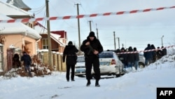 An armed policeman stands guard as police experts examine the scene of the incident in the small town of Knyazichi, some 30 kilometers east of Kyiv, on December 4.