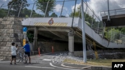 Copiii privesc o porțiune de drum prăbușită în orașul Hikawa, din prefectura Kumamoto, pe 29 iulie 2026, după ce, cu o zi înainte, un cutremur a lovit sud-vestul Japoniei.