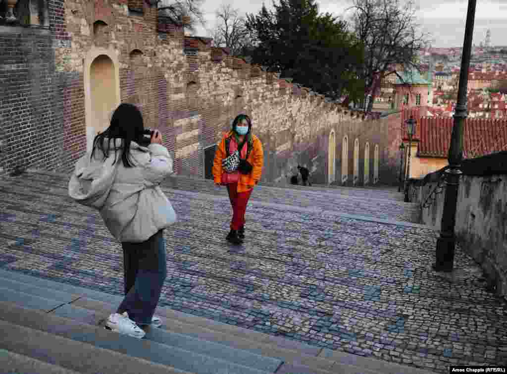 Tourists shoot photographs while wearing surgical masks near Prague Castle.&nbsp;