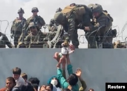 Vojnik uzima bebu preko žičane ograde 19. avgusta.