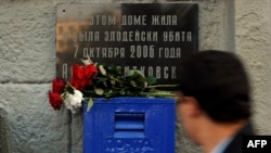 A man walks past a marble plaque on the apartment building where journalist and rights activist Anna Politkovskaya was killed in 2006. 