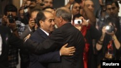 Liwiýada häkimiýetiň Milli assambleýa geçirilmeginden soň, Milli geçiş geňeşiniň başlygy Mustafa Abdel Jalil (sagda), uruş döwrüniň premýer-ministri Mahmud Jibril bilen gujaklaşýar. 8-nji awgust, 2012 ý.