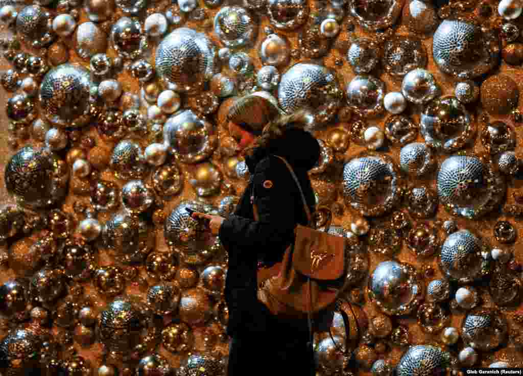 A woman uses her mobile phone as she walks past a shopping mall entrance with Christmas decorations in central Kyiv, Ukraine. (Reuters/Gleb Garanich)