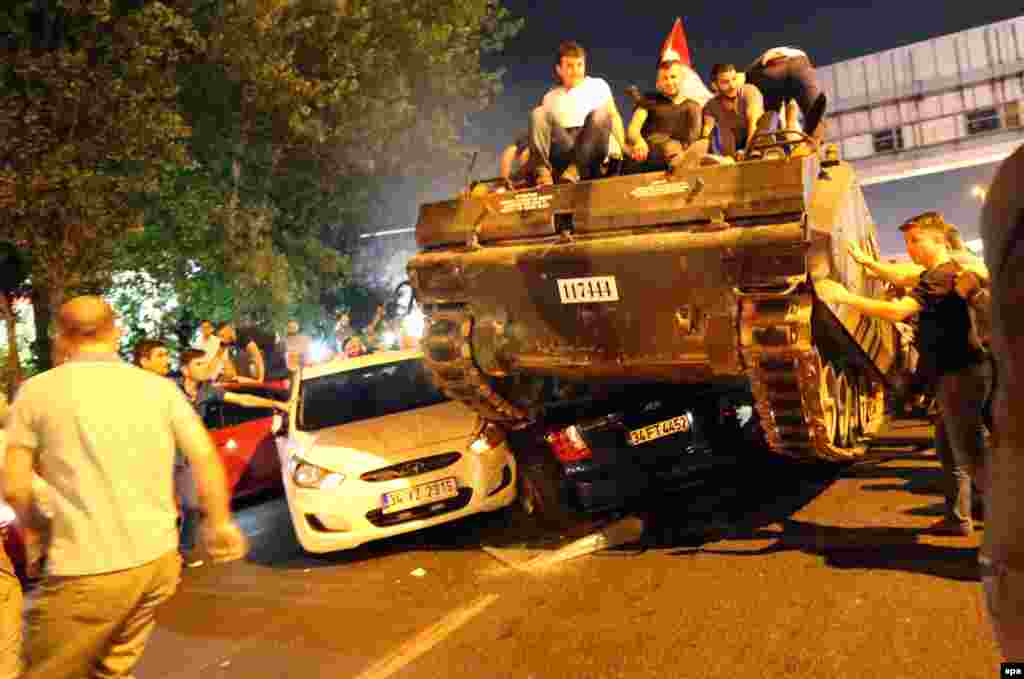 People ride atop a tank as it runs over cars on a road in Istanbul, Turkey, amid an attempted coup on July 16. Turkish officials have rounded up thousands of people suspected of involvement in the failed military coup attempt and have locked down a key air base used for U.S.-led air strikes against Islamic State militants. (epa/Tolga Bozoglu)