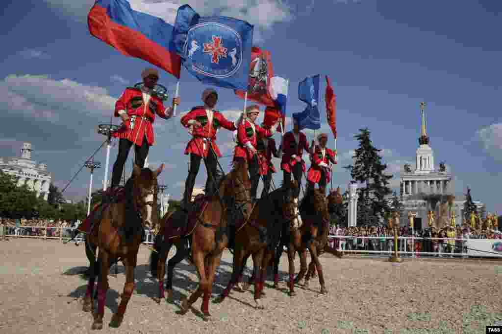 Riders from a joint team of the Presidential Regiment Cavalry Escort and the Kremlin Horse Riding School perform during a horse stunt show at the All-Russian Exhibition Center in Moscow. (ITAR-TASS/Sergei Savostyanov)