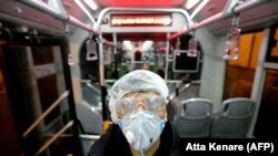 Un lucrător al Primăriei din Teheran dezinfectează un autobuz