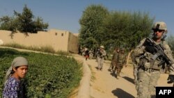 Afghanistan -- Afghan children watch as US soldiers of the 2nd Platoon Alpha 3-71 Cavalry walk past during a patrol mission at Sadrland village in the Baraki Barak district of Logar Province, 14Aug2009