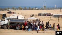 Raseljeni Palestinci stoje u redu da kupe vodu, pored svog privremenog kampa u Rafi, Pojas Gaze, 17. maj 2024.