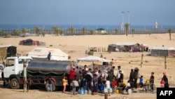 Raseljeni Palestinci čekaju u redu za vodu ispred privremenog kampa u Rafahu, 17. maja 2024.