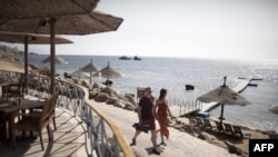 Туристы идут вдоль побережья Красного моря на египетском курорте Шарм-эль-Шейх.