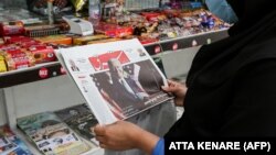 A woman browses the front page of the Iranian newspaper Sharq featuring the 2020 U.S. election results at a newsstand in Tehran on November 8, 2020.