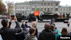 Зрители наблюдают за грузовиком, перевозящим советский танк Т-34 после военного парада в День Победы. Москва, 9 мая 2023 года