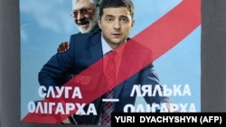 A placard depicting Kolomoyskiy and then-presidential candidate Volodymyr Zelenskiy in Lviv in February 2019. It reads: "Servant of Oligarch, Doll of Oligarch." Kolomoyskiy's television station is credited with helping the political novice win in a landslide against incumbent Petro Poroshenko.