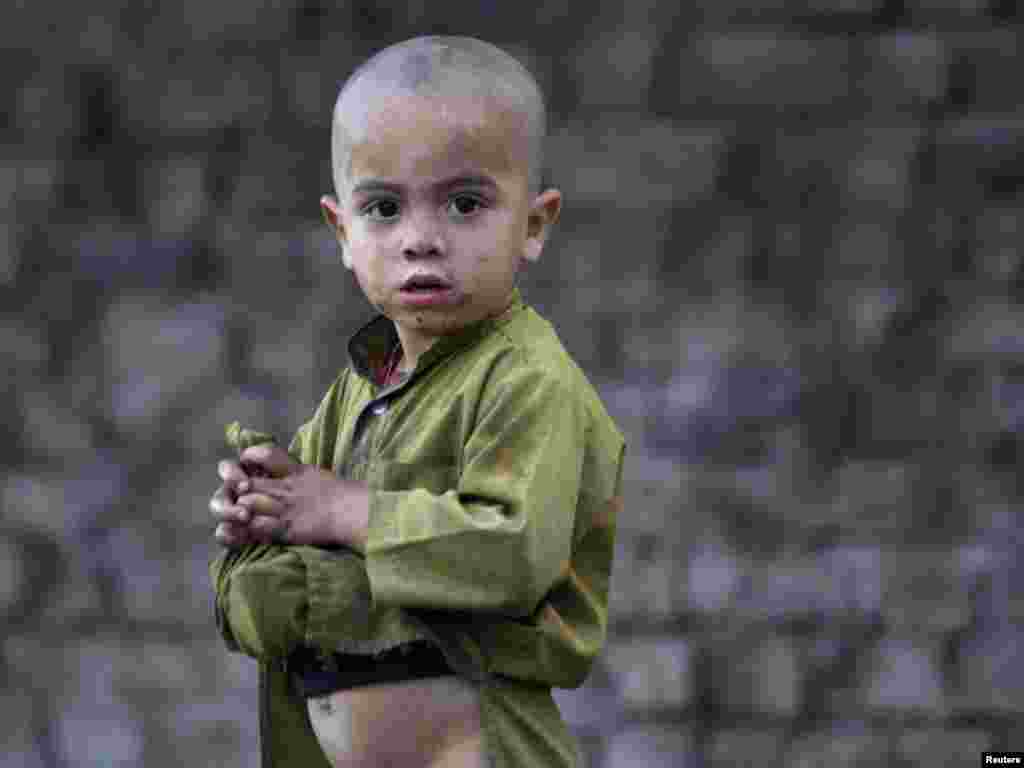 An Afghan migrant boy uses his shirt to collect vegetables and fruit to eat from a dump on the outskirts of Peshawar on April 3. Photo by Fayaz Aziz for Reuters