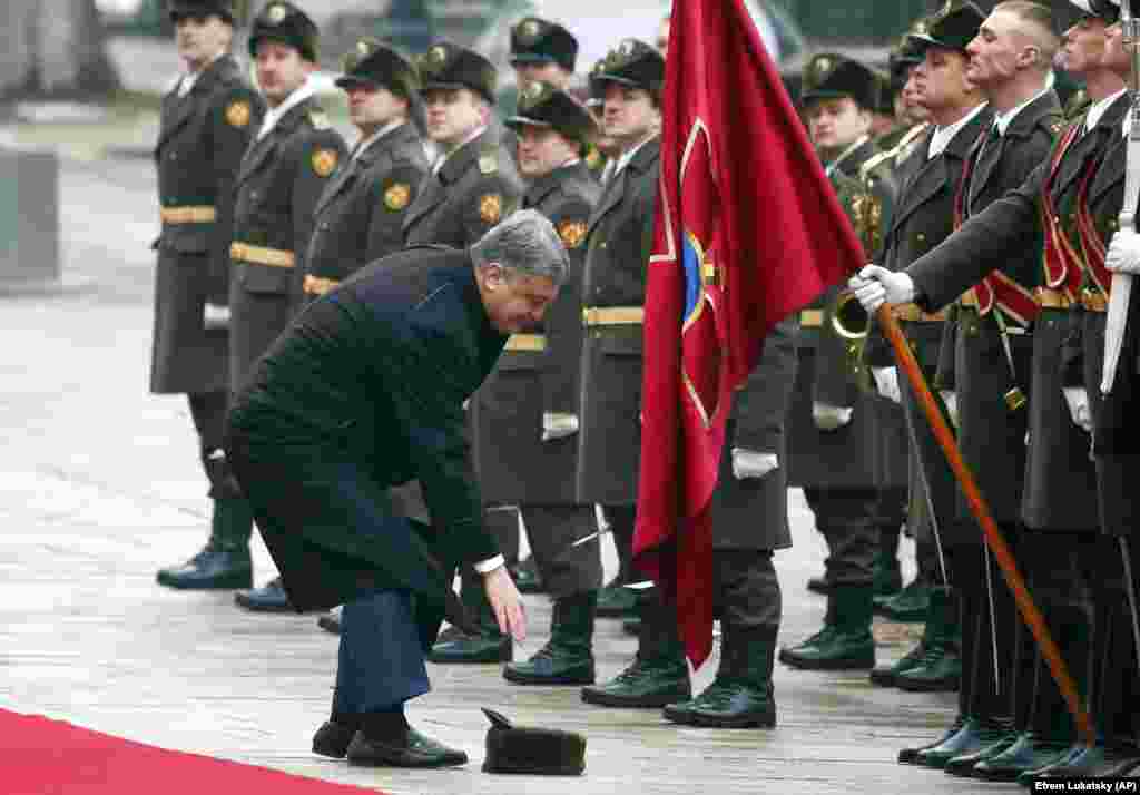 Ukrainian President Petro Poroshenko picks up the hat of a military soldier as he and Austrian President Alexander Van der Bellen review the honor guard during a welcoming ceremony ahead of their meeting in Kyiv on March 14. (AP/Efrem Lukatsky)