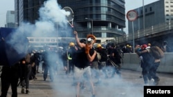 یکی از معترضان در تظاهرات روز شنبه گلوله گاز اشک‌آور را با راکت تنیس دفع می‌کند