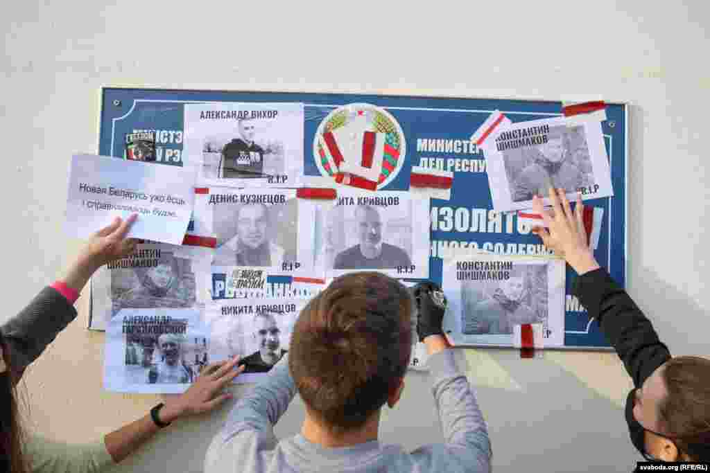 Протестующие вешают плакаты на двери следственного изолятора на улице Окрестина