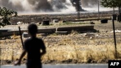 Мальчик в турецком городке Каркамыш на фоне дыма, вьющегося над сирийским пограничным городом Джераблусом, 1 сентября 2016 года. 