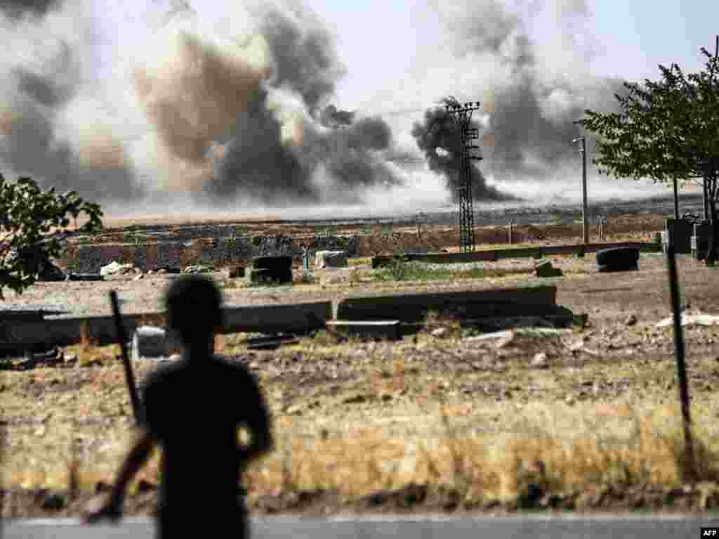 ბიჭი თურქეთის ქალაქ კარკამისიდან უყურებს კვამლს, რომელიც სირიის ქალაქ ჯარაბულუსის მახლობლად ადის ცაში.&nbsp;