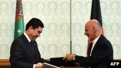 Afghan President Ashraf Ghani (R) exchanges documents with Turkmen President Gurbanguly Berdymukhammedov in Kabul on August 27.