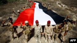 جنود عراقيون يرفعون علماً كبيراً في جرف الصخر