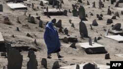 زن افغان با چادری هنگام عبور از یک قبرستان