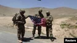 NATO soldiers stand with a U.S. flag after a security handover ceremony at a military academy outside Kabul in June.