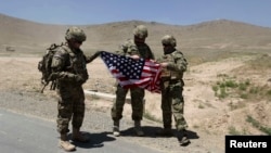NATO soldiers stand with a U.S. flag after a security handover ceremony at a military academy outside Kabul in June.