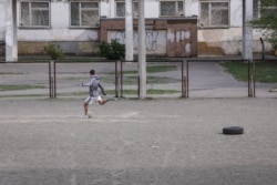 Молодий футболіст тренується на спортмайданчику школи в районі вулиці Радунської