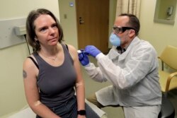 A U.S. pharmacist gives a test subject an injection in a first-stage safety-study clinical trial of a potential vaccine for COVID-19 in Washington.