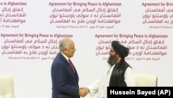 U.S. envoy Zalmay Khalilzad (left) and Mullah Abdul Ghani Baradar, the Taliban group's top political leader, shake hands after signing a peace agreement in Doha on February 29.
