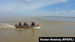 Спасатели перевозят жителей села Аганас на лодке по затопленной местности. Акмолинская область, 20 апреля 2015 года.
