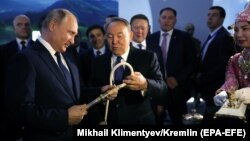 Нурсултан Назарбаев в бытность президентом Казахстана и его российский коллега Владимир Путин рассматривают камчу на туристической выставке. Петропавловск, 9 ноября 2018 года.
