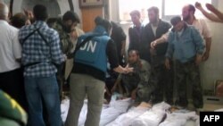 A photo released by the Syrian opposition shows UN observers inspecting the bodies of the 92 victims, more than 30 of them young children. The UN called the deaths a "brutal breach" of international law.