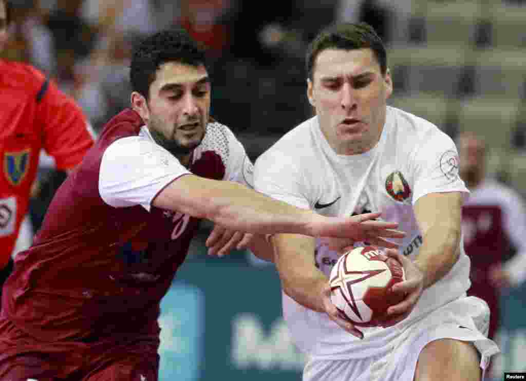 Abdulla Al-Karbi of Qatar and Barys Pukhouski of Belarus (right) run for the ball during their preliminary round of the 24th men's handball world championship in Doha. (Reuters/Mohammed Dabbous)