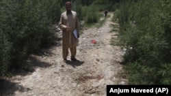 A plainclothes police officer indicates the bloody spot where popular Pakistani blogger and social-media activist Muhammad Bilal Khan was killed in Islamabad on June 16.