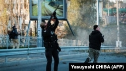 Ukrán rendőr próbál lelőni egy közeledő kamikazedrónt Kijevben 2022. október 17-én