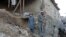 Pakistani residents gather next to the rubble of damaged house following an earthquake in Bajaur on October 26.