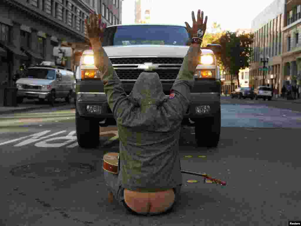 Un activist al mișcării &bdquo;Occupy Oakland&rdquo; blochează traficul l&icirc;ngă Frank Ogawa Plaza la 14 noiembrie. (REUTERS/Robert Galbraith)